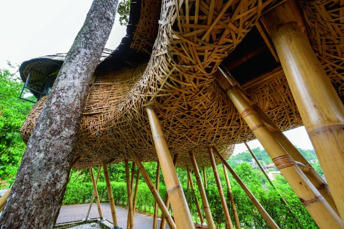 A photograph of an open meditation site made with an inter-woven bamboo rooftop supported by bamboo poles.