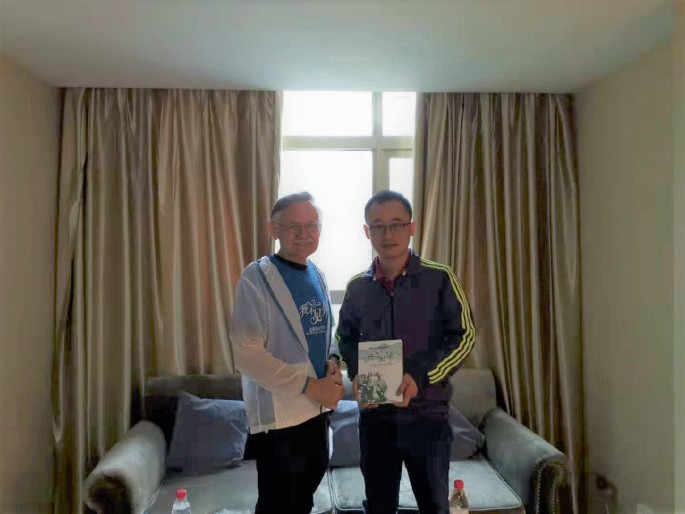 A photograph of William Brown and Tibet assistance official Wu Qiong, who is holding a book.