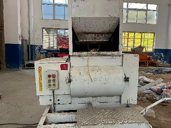 A photo of an old, dirty industrial machine in a cluttered workshop.