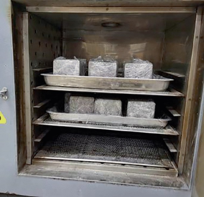 A photograph displays geopolymer concrete specimens arranged in a high-temperature curing box in 2 rows.