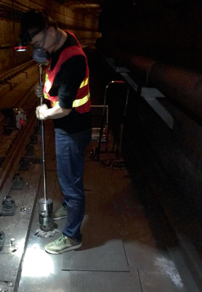 A photograph of a worker with a tool to inspect the tracks.