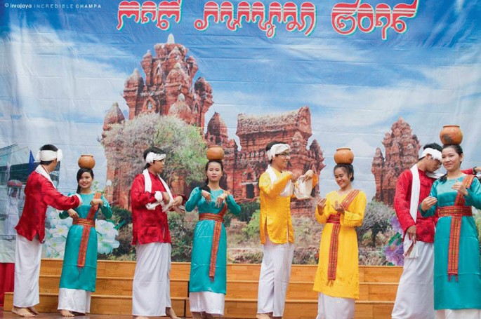 A poster depicts 4 pairs of young men and women in traditional wear in dance movements against the background of a temple. The women have pots on their heads.