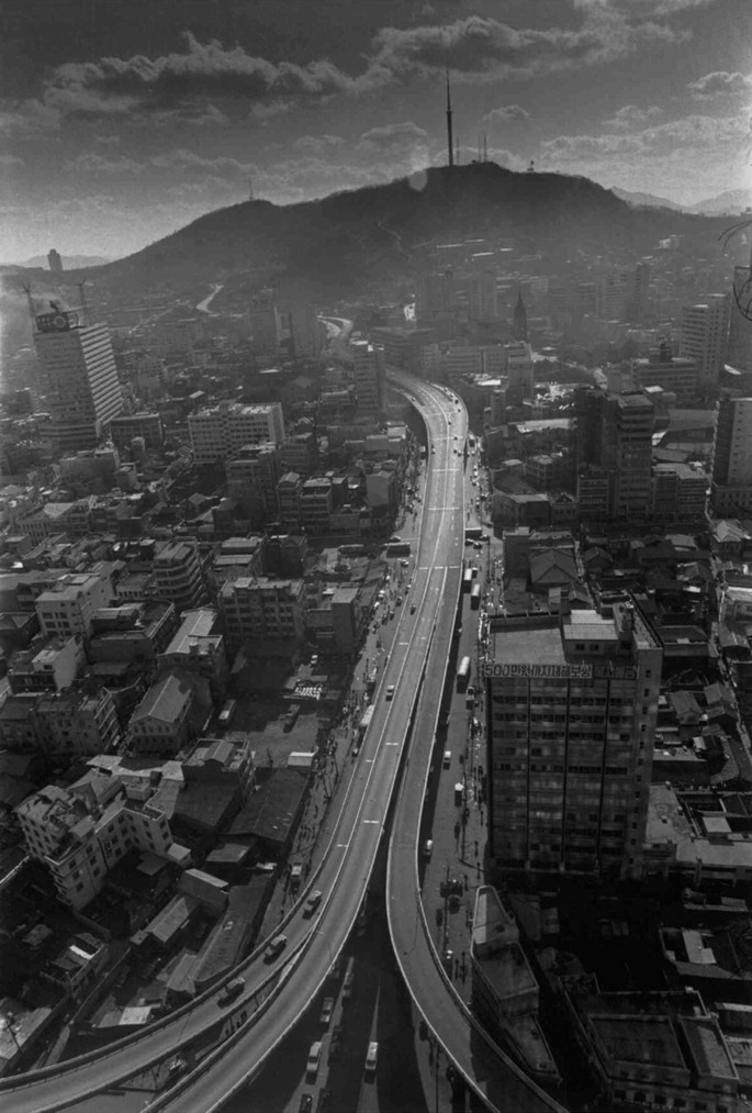 An aerial photograph of Cheonggyecheon Highway with an elevated highway that is diverged into three roads and one ground level highway. High rise buildings are on both sides of the highway.
