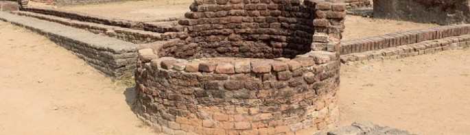A photograph of an ancient well and drainage system of the Indus Valley Civilization. The well and drain channels are made of bricks.