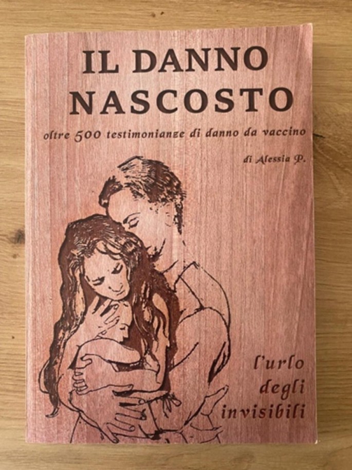 A photo of the front cover of a book placed on a wooden desk, has a sketch of a woman holding a baby and a man embracing them from behind. Book title and other text is in a foreign language.