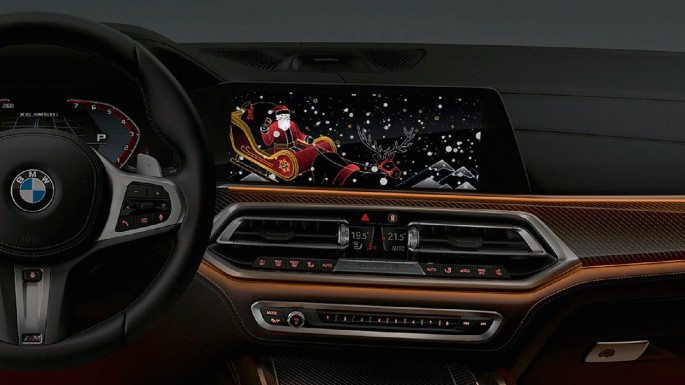 A photograph depicts the interior of a B M W car with a digital display featuring an animated Santa Claus riding a sleigh.
