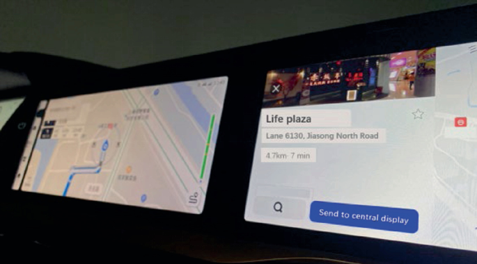 A photograph depicts the infotainment system of a car. On the left side of the screen, there is a navigation map displayed. On the right side, information about a location called Life Plaza is displayed.