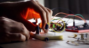 A light from a circuit board illuminates a student's hand.