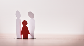 Paper cutout of a little girl in red standing between paper cutouts of two adults.