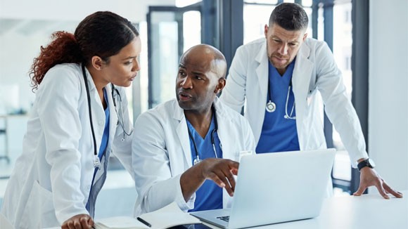 A group of medical practitioners working on a laptop together