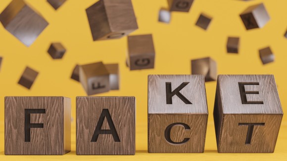 Fake or Fact Concepts with Wooden Text Alphabet Block on Yellow Background