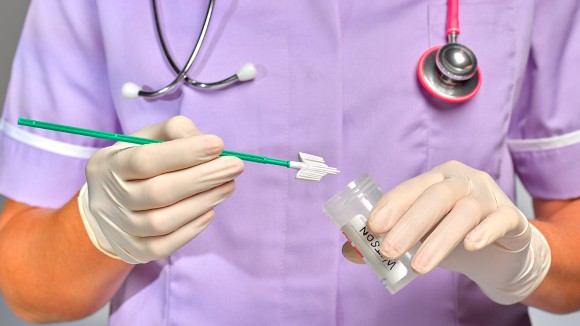 Practice Nurse/doctor wearing gloves and inserting a test into a specimen container