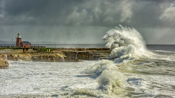 Big wave crashing by the coast, near a lighthouse, stormy weather, El Niño