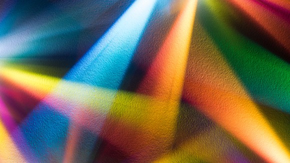Multi colored light beams emitting on paper texture background