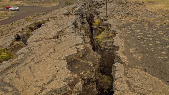 Large fissure in the ground with mountains in the background