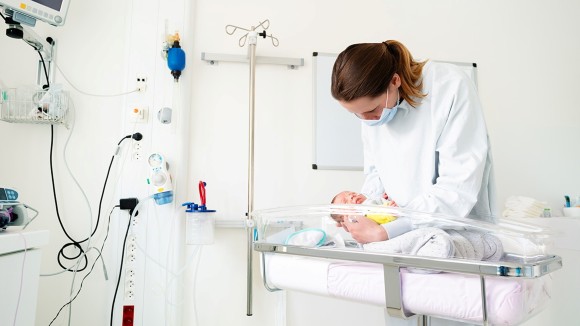 Nurse in NICU examining small infant
