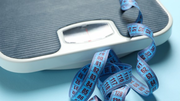Scales and measuring tape on blue background. Weight loss concept