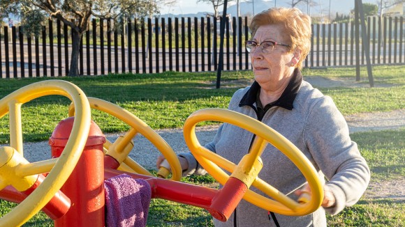 Elderly woman practices sport moving the spinning wheels in a bio-healthy park