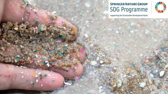 Close-up side shot of hands shows microplastic waste contaminated with the seaside sand. Microplastics are contaminated in the sea. Concept of water pollution and global warming.