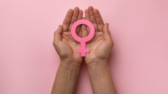 Woman holding female gender sign on pink background