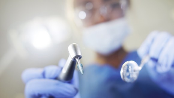 Close up on surgical drill held by gloved hands