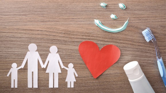 Family and heart cut out of paper with smiling toothpaste and oral health products
