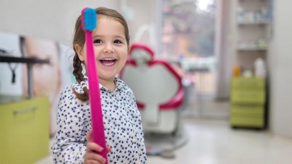 Young girl with a big toothbrush