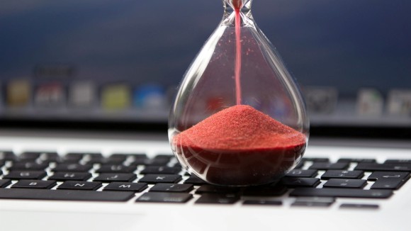 image of an hourglass with red sand sitting on a computer keyboard