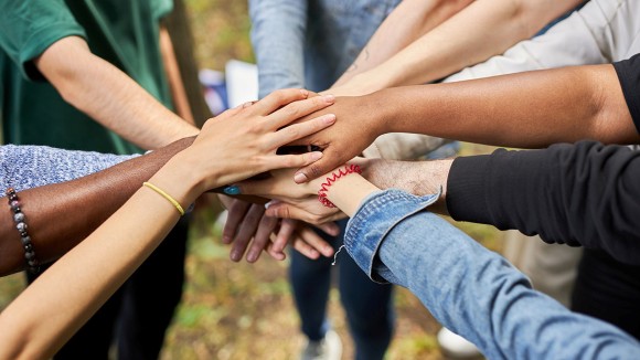 Multiple people putting their hands together in a circle