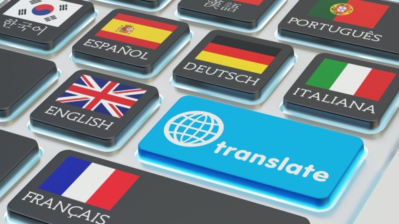Foreign languages translation concept. Macro view of computer keyboard with national flags of world countries on keys and blue translate button
