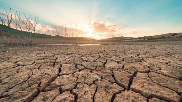dry reservoir in foreground, against the backdrop of a sunset