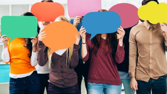 A crowd of individuals each covering their faces with blank, colorful cartoon text boxes 