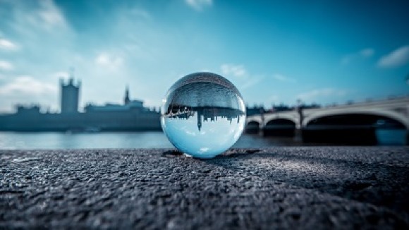 crystal ball in front of river thames with a bridge and big ben in the background