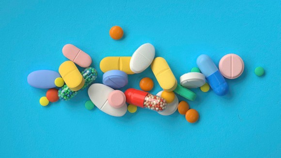 Pile of colourful pills on a blue background, 3D rendering, conceptual image