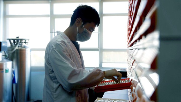 Man in labatortory looking at a range of test tubes