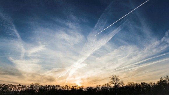 beautiful sunset with what looks like manufactured cloud formations from airplanes all over the area with metallic shiny colors