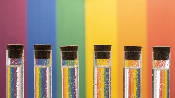 Test tubes filled with rainbow colours on a rainbow background.