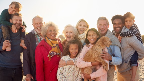 Portrait Of Multi-Generation Family Group With Dog On Winter Beach Vacation