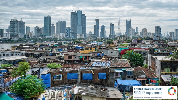Slums in Mumbai with a backdrop of city skyscrapers in the distance.