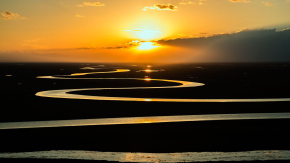 The sun sets over a meandering river