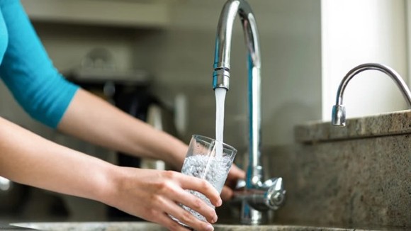 person filling up glass with tap water