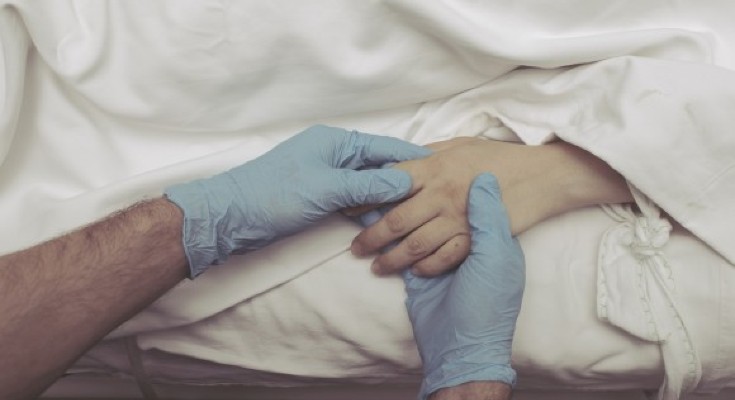 medical professional hands in blue gloves holding hand of a patient