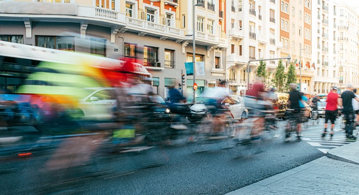 blurred group of cyclists riding through a city center