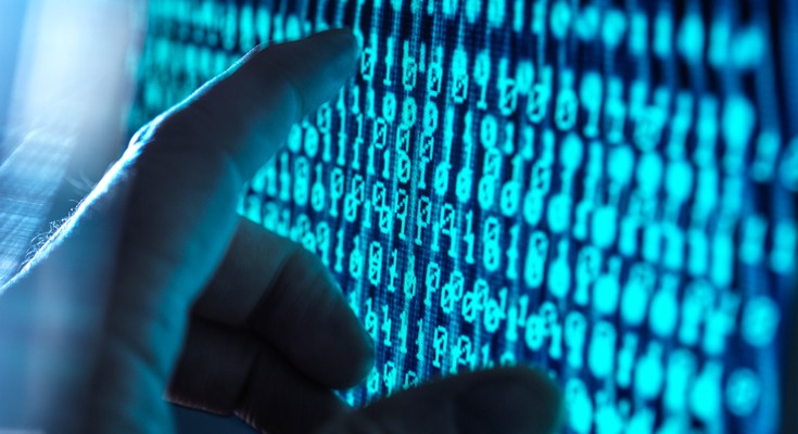 Hand about to touch a computer screen with data streaming through