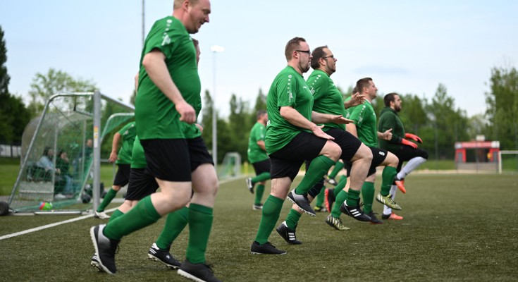 Members of a football team wearing a green kit warm up before their match