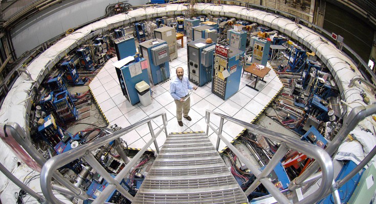 An image from above with a man standing in the centre of a large ring metal, surrounded by machinery