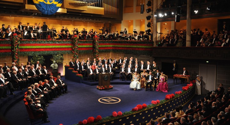 A ceremony to award the Nobel Prizes at Stockholm Concert Hall in 2008. There are many people in formal wear on a stage, and in an audience