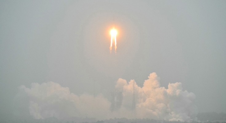 A firey orange ball hurtles over the clouds in a gray sky
