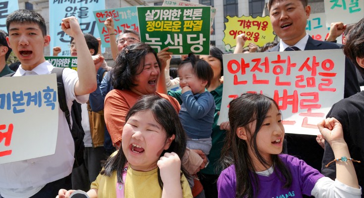A crowd of people with protest signs written in Korean