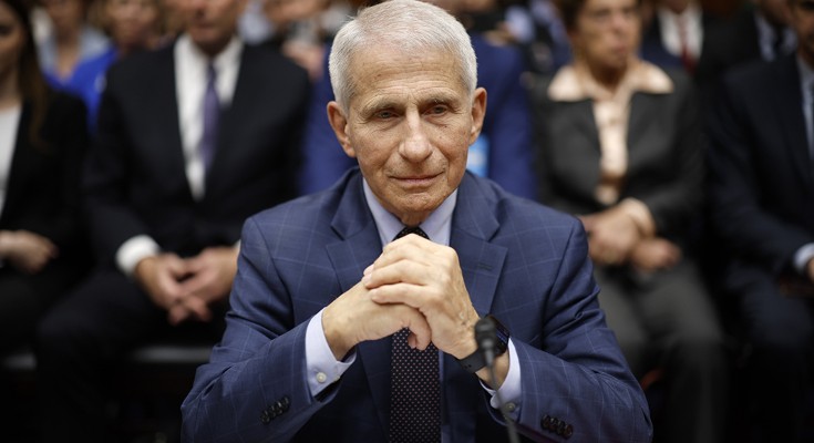 Anthony Fauci puts his hands in front of him on the table, with a microphone in front of him, as he testifies before a congressional committee in the U.S.